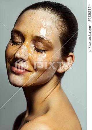 Portrait of happy beautiful young brunette woman with freckles and honey on face with closed eyes and smile happiness face. indoor studio shot isolated on gray background. 89868534