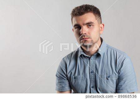 Closeup portrait of handsome unhappy man with bad mood. Actors portfolio picture, emotion and feelings. Studio shot, isolated on gray background Closeup portrait of handsome unhappy man with bad mood. Actors portfolio picture, emotion and feelings. Studio shot, isolated on gray background 89868536