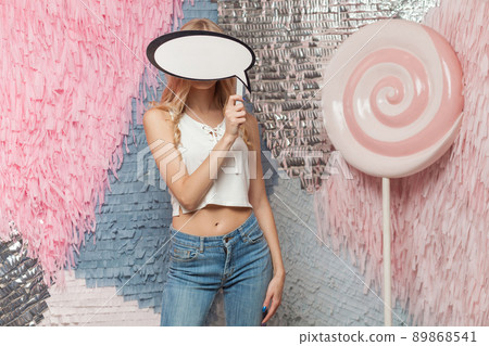 Portrait of woman with blondie long hair holding speech bubble for your text on abstract background with huge lollipop Portrait of woman with blondie long hair holding speech bubble for your text on abstract background with huge lollipop 89868541