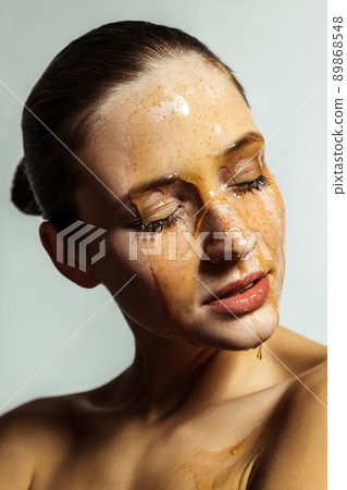 Portrait of happy beautiful young brunette woman with freckles and honey on face with closed eyes and smile happiness face. indoor studio shot isolated on gray background. Portrait of happy beautiful young brunette woman with freckles and honey on face with closed eyes and smile happiness face. indoor studio shot isolated on gray background. 89868548