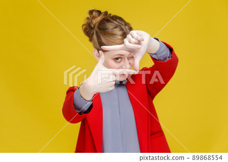 Red head business woman in red suit showing frame,crop sign. Studio shot, isolated on yellow background 89868554