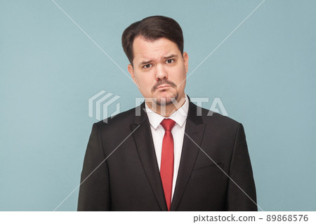 Sad, looser businessman, crying, looking at camera and hope. Need a new job and money. isolated on light blue background. handsome businessman with black suit, and mustache looking at camera. Sad, looser businessman, crying, looking at camera and hope. Need a new job and money. isolated on light blue background. handsome businessman with black suit, and mustache looking at camera. 89868576