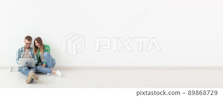 Planning summer vacation or online order. Cute young couple searching hotel and resort online using laptop on floor at home - white background banner with copy space and place for advertising 89868729