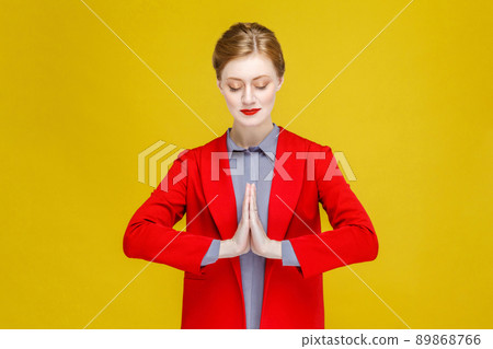 Pray, wish, religion. Red head well dressed woman meditating. Studio shot, isolated on yellow background Pray, wish, religion. Red head well dressed woman meditating. Studio shot, isolated on yellow background 89868766