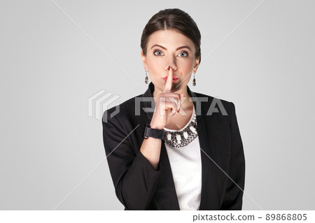 Secret. Boss woman showing shh, quiet sign. Studio shot, indoor. Isolated on grey background Secret. Boss woman showing shh, quiet sign. Studio shot, indoor. Isolated on grey background 89868805