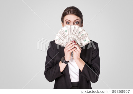 Funny woman showing many cash, dollar and . sStudio shot, indoor. Isolated on grey background 89868907