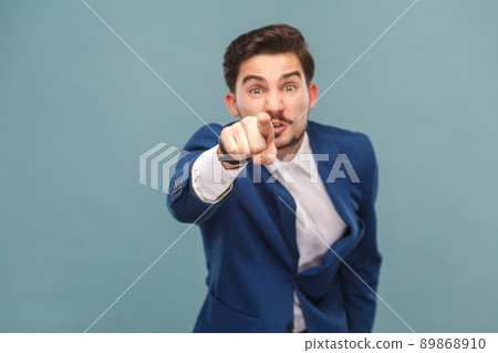 Hey you! Expressive man pointing finger at camera. Business people concept, richly and success. Indoor, studio shot on light blue background 89868910