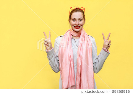 Young beautiful redhead woman showing peace sign. Isolated studio shot on yellow background. Young beautiful redhead woman showing peace sign. Isolated studio shot on yellow background. 89868916