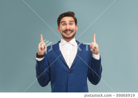 Happiness man pointing finger up at copy space . Business people concept, richly and success. Indoor, studio shot on light blue background 89868919
