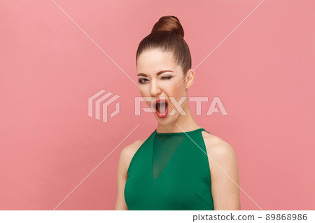 Beautiful fashionable woman flirt and wink at camera. Expression emotion and feelings concept. Studio shot, isolated on pink background 89868986