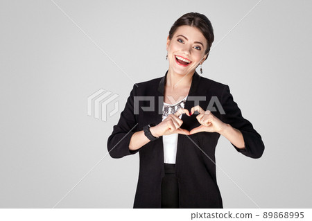 Love concept. Creative woman showing heart shape sign. Studio shot, indoor. Isolated on grey background 89868995