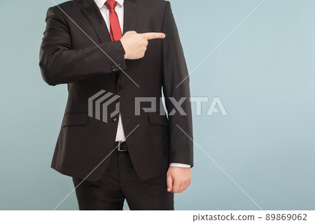 Closeup portrait of unknown businessman points to an empty space for your advertisement.. Indoor, studio shot, isolated on light blue or gray background 89869062