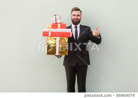 Happiness businessman toothy smile, holding box and thumbs up. Studio shot, gray background Happiness businessman toothy smile, holding box and thumbs up. Studio shot, gray background 89869079