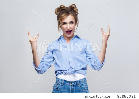 Rock n roll. Funny lady looking at camera with rock sing. Studio shot, on gray background. 89869081