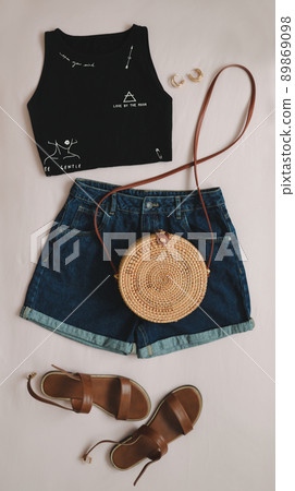 flat lay composition with female top, denim shorts, sandals and a wicker rattan bag on beige background top view flat lay composition with female top, denim shorts, sandals and a wicker rattan bag on beige background top view 89869098