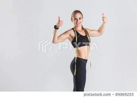 Closeup powerful muscular girl, showing thumbs up at camera and smiling. Studio shot, gray background 89869283