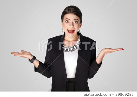 Wow! Businesswoman with big eyes, toothy smile and shocked. Studio shot, indoor. Isolated on grey background Wow! Businesswoman with big eyes, toothy smile and shocked. Studio shot, indoor. Isolated on grey background 89869285