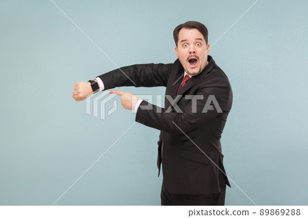 Man showing at new model better smart watch. indoor studio shot. isolated on light blue background. handsome businessman with black suit, red tie and mustache looking at camera. Man showing at new model better smart watch. indoor studio shot. isolated on light blue background. handsome businessman with black suit, red tie and mustache looking at camera. 89869288