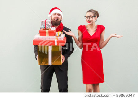 Its so hard and i tired! Not my problem, everything fine. Bearded man holding many gift box and crying, women looking at camera, toothy smiling and hands on sides and say so what? Studio shot 89869347