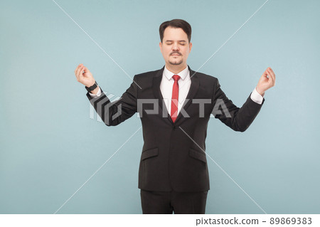 Businessman closed eyes, standing and doing yoga pose to calm down and stop hating the boss you need to do yoga. isolated on light blue background. handsome businessman with black suit and mustache. 89869383