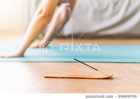 Girl doing yoga at home on rug in front of smoldering incense 89869399