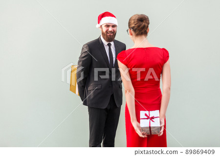 Surprised concept. Happiness friends standing each other and holding gift box behind spine. Studio shot, gray background 89869409