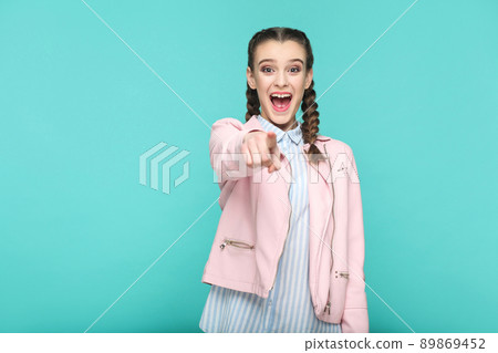 wow, amazed portrait of beautiful cute girl standing with makeup and brown pigtail hairstyle in striped light blue shirt pink jacket. indoor, studio shot isolated on blue or green background. 89869452