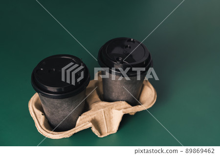 Disposable cups on stand against green background Disposable cups on stand against green background 89869462