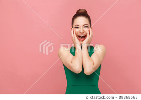 Perfect woman wearing green dress toothy smiling. Expression emotion and feelings concept. Studio shot, isolated on pink background 89869565