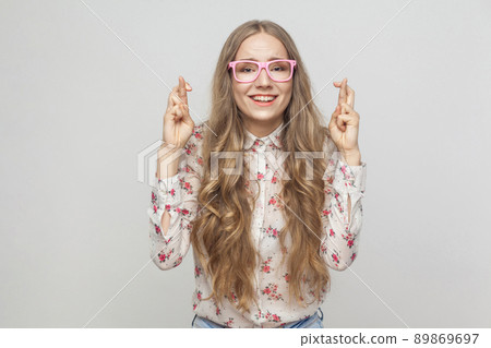 Emotional girl showing good luck sign her fingers, looking at camera and toothy smiling. Studio shot, gray background Emotional girl showing good luck sign her fingers, looking at camera and toothy smiling. Studio shot, gray background 89869697