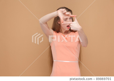 crop or good cutout composition choosing. portrait of emotional cute, beautiful woman with makeup and long hair in pink dress. indoor, studio shot, isolated on light brown or beige background. 89869701