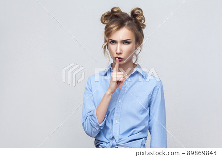 Shh sign. Anger woman looking at camera with silent sign. Studio shot, on gray background. 89869843