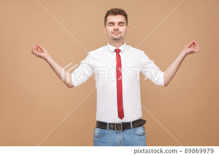 Relaxed businessman doing yoga poses. Business people concept, good and bad emotion and feelings. Studio shot, isolated on light brown background Relaxed businessman doing yoga poses. Business people concept, good and bad emotion and feelings. Studio shot, isolated on light brown background 89869979