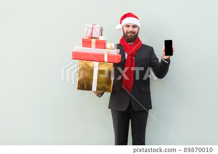 No way! New year sale! Online shopping. Businessman holding hands phone and looking at camera with smiley face. Indoor, studio shot. Isolated on gray background 89870010