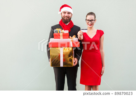 Happiness couple after shopping. Showing gifts, box and discount card. Toothy smiling and looking at camera. Studio shot 89870023