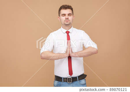Relaxed businessman doing yoga . Business people concept, good and bad emotion and feelings. Studio shot, isolated on light brown background Relaxed businessman doing yoga . Business people concept, good and bad emotion and feelings. Studio shot, isolated on light brown background 89870121