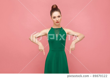 Here and now! Woman pointing finger at copy space. Expression emotion and feelings concept. Studio shot, isolated on pink background Here and now! Woman pointing finger at copy space. Expression emotion and feelings concept. Studio shot, isolated on pink background 89870122