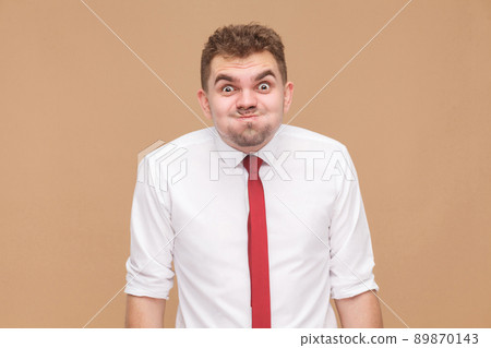 What? Crazy funny man with big eye looking at camera. Business people concept, good and bad emotion and feelings. Studio shot, isolated on light brown background 89870143