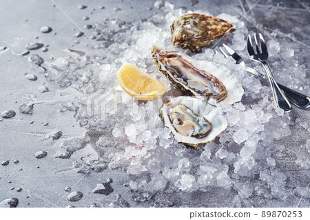 Oysters with lemon on ice on gray background close-up 89870253