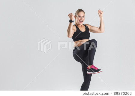 Successful and happiness fitness woman rejoice her victory and toothy smiling. Studio shot, gray background Successful and happiness fitness woman rejoice her victory and toothy smiling. Studio shot, gray background 89870263