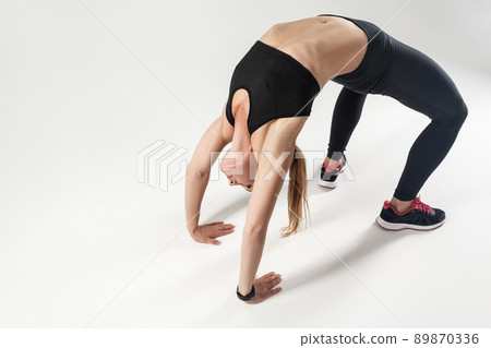 Pilates pose. Athletic woman doing hard exercising. Indoor shot, gray background 89870336