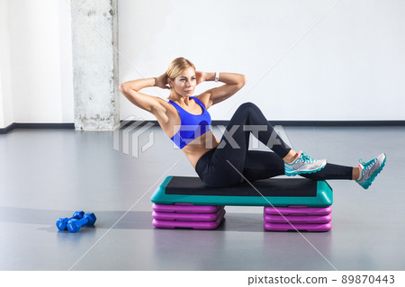 Profile woman lie on step platform and doing press aerobic. Studio shot 89870443