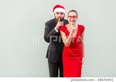 Shh sign. Big secret, shut up! Well dressed businessman and woman looking at camera and showing quiet sign. Studio shot 89870491
