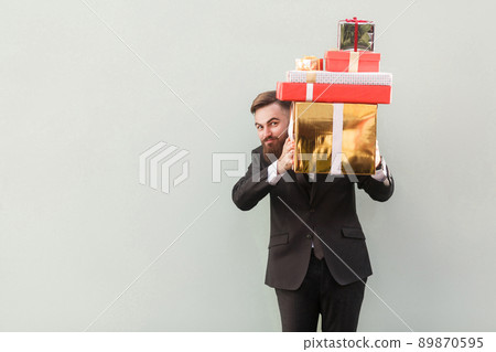 Funny man hiding behind boxes and looking at camera. Studio shot. Isolated on gray background Funny man hiding behind boxes and looking at camera. Studio shot. Isolated on gray background 89870595