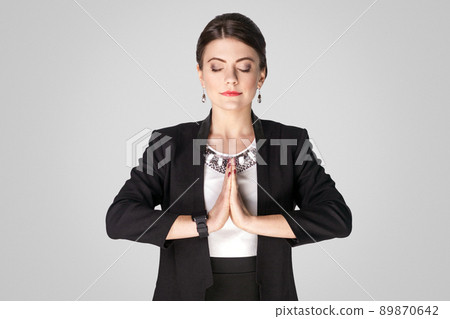 Business woman pray, and wish. Studio shot, indoor. Isolated on grey background Business woman pray, and wish. Studio shot, indoor. Isolated on grey background 89870642