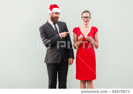 Sneer and mock concept. Man pointing fingers at woman and smiling. Woman crying and holding bad gift. Studio shot Sneer and mock concept. Man pointing fingers at woman and smiling. Woman crying and holding bad gift. Studio shot 89870673