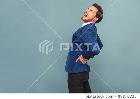 Man have pain in back. Stones or kidneys organs. portrait of handsome bearded businessman in blue suit and white shirt. Indoor studio shot, isolated on light blue background 89870723
