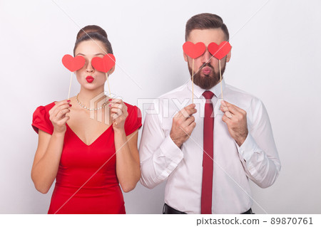 Handsome couple holding decorative sign love, heart symbol. Indoor, studio shot, isolated on gray background 89870761
