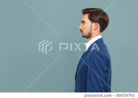 side view or profile view of serious handsome bearded businessman in blue suit and white shirt. Indoor studio shot, isolated on light blue background side view or profile view of serious handsome bearded businessman in blue suit and white shirt. Indoor studio shot, isolated on light blue background 89870793