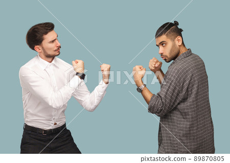 profile side view of two angry boxer businessman, looking to each other with serious face and ready to attack. crisis and partnerships problem. indoor studio shot, isolated on light blue background. profile side view of two angry boxer businessman, looking to each other with serious face and ready to attack. crisis and partnerships problem. indoor studio shot, isolated on light blue background. 89870805